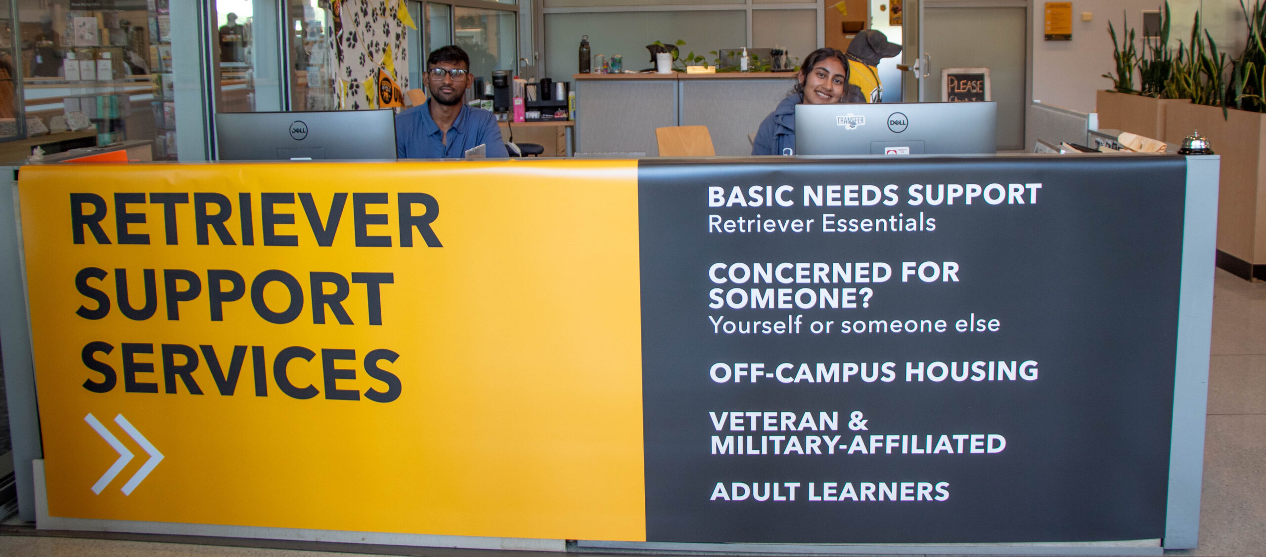 Two friendly students sitting behind the Retriever Support Services desk.